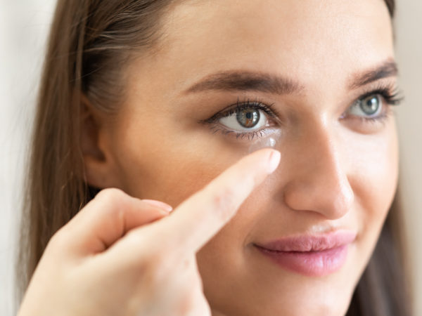 Beauty, Vision And Eyesight Concept. Closeup portrait of smiling lady applying soft eye lens. Happy woman inserting and trying on contacts for vision and eyesignt, holding it on finger, banner